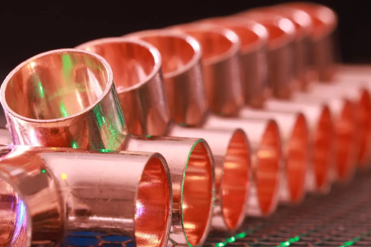 Row of shiny copper pipe fittings lined up