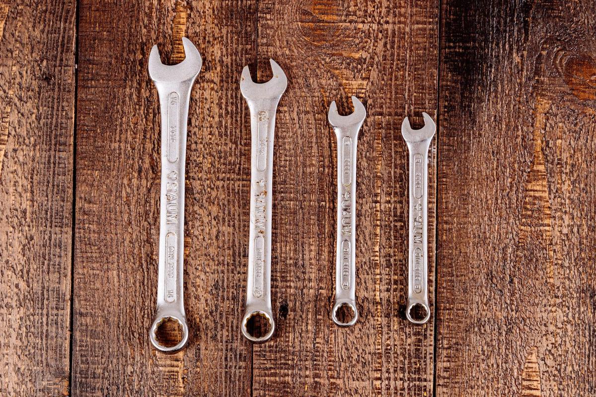 Four combination wrenches laid on a wooden surface
