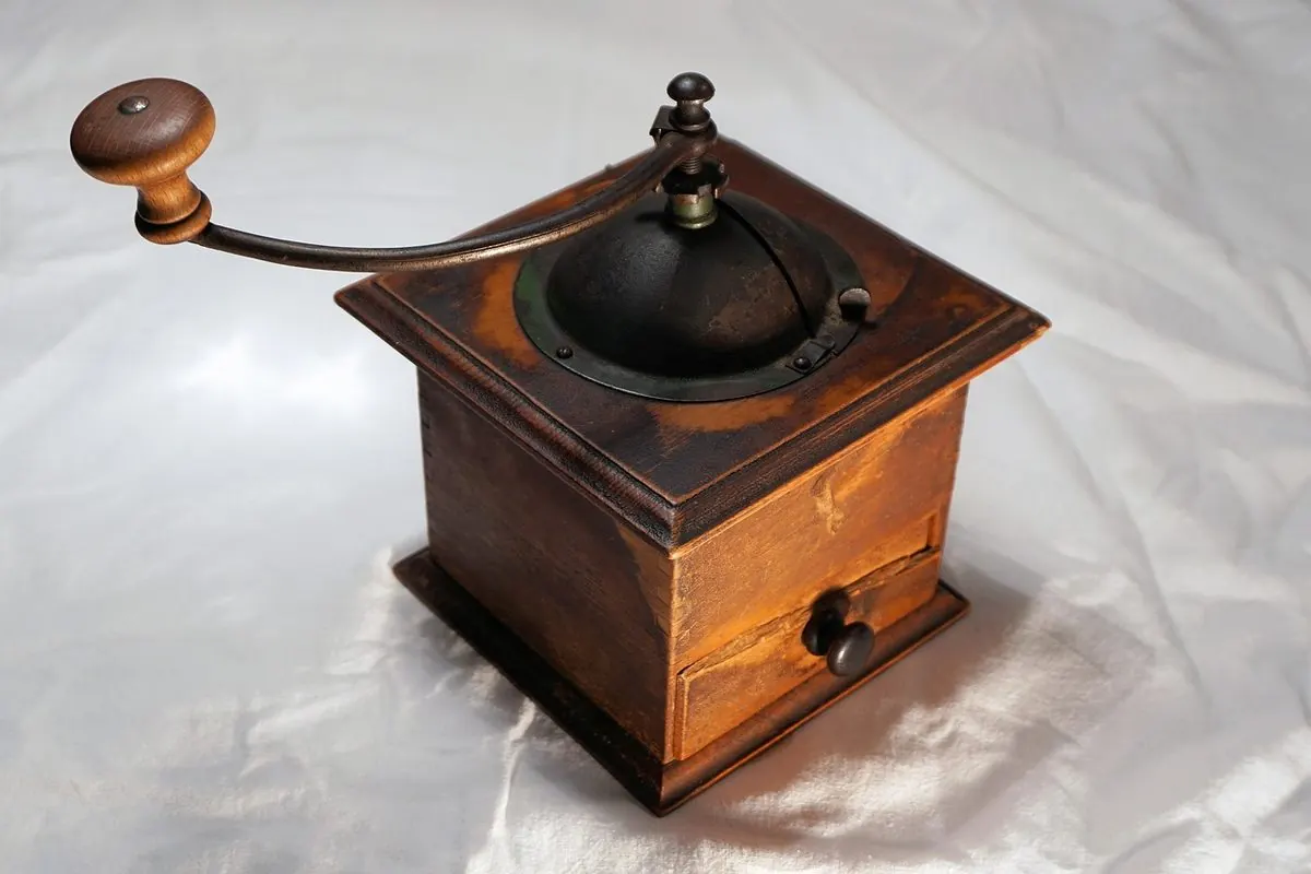 Old wooden hand-crank coffee grinder with a drawer