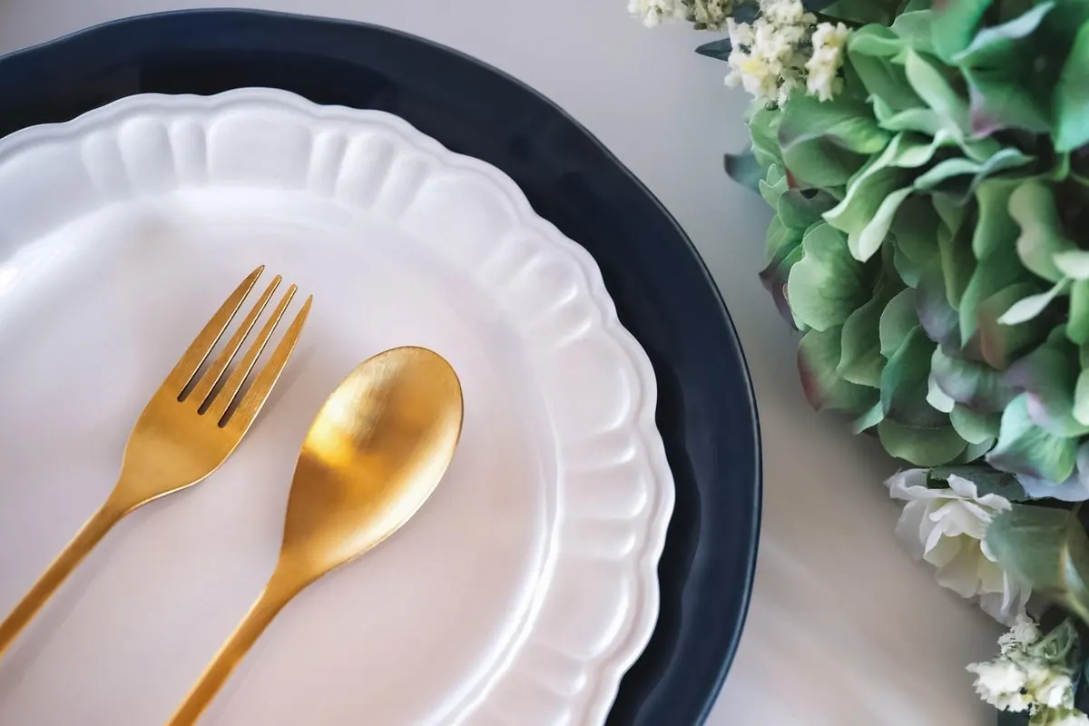 Thìa và dĩa mạ vàng đặt trên đĩa sứ trắng