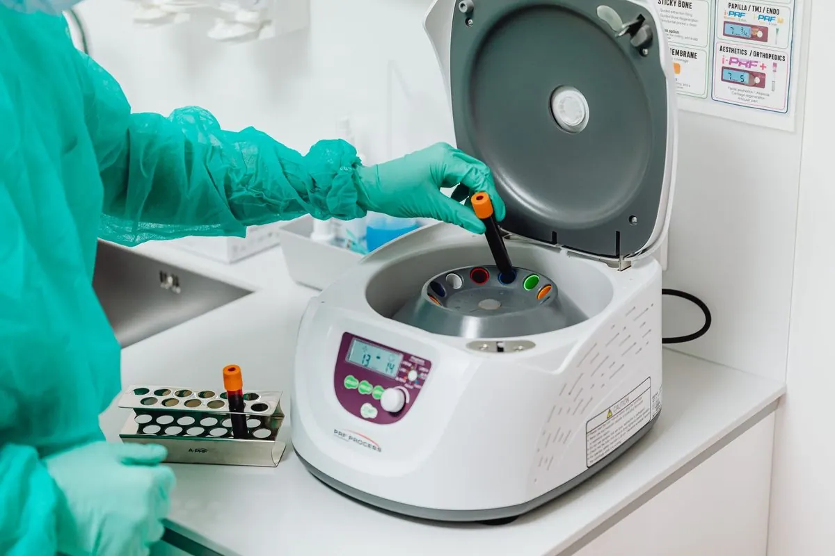Open laboratory centrifuge with a sample tube being loaded