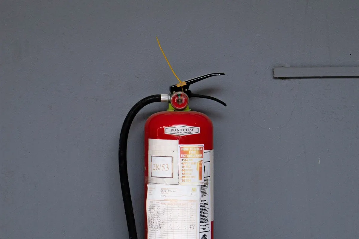 Red fire extinguisher standing against a wall