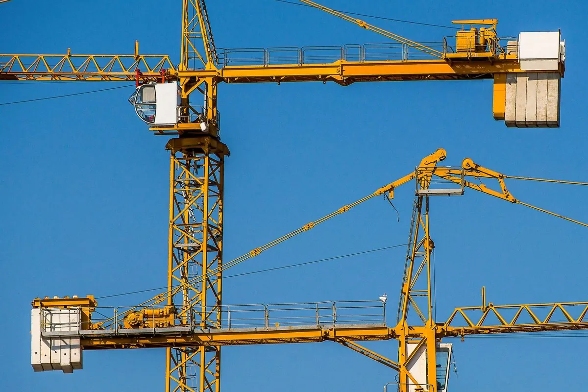 Yellow tower cranes against a blue sky