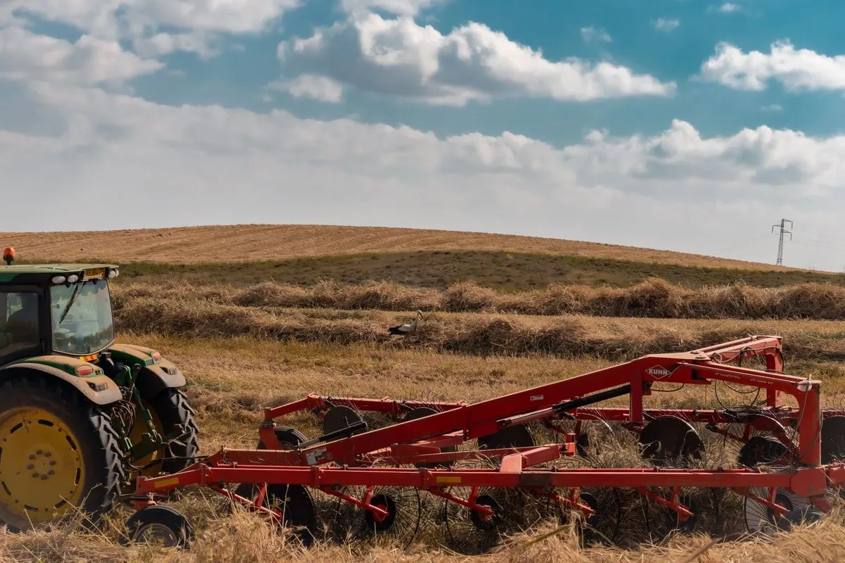 Red disc harrow behind a tractor in a field