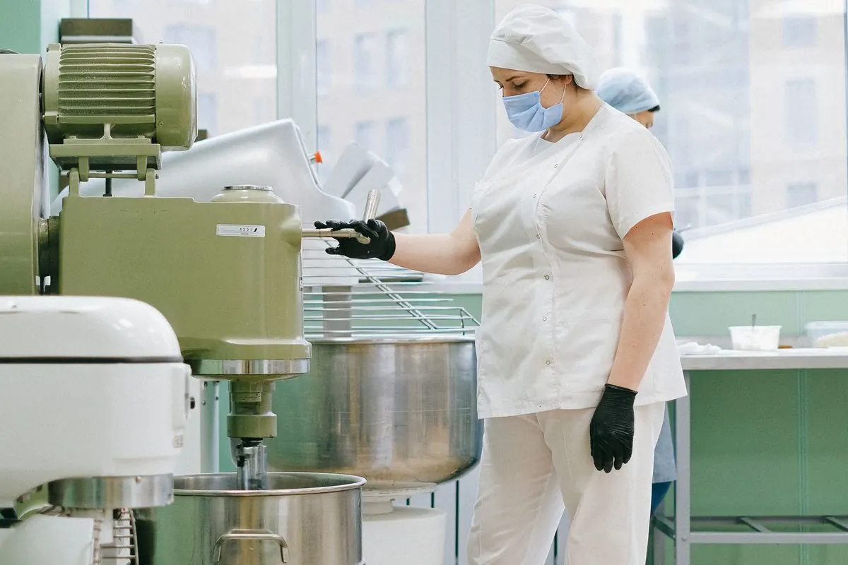 Worker beside dough mixers in a bakery plant