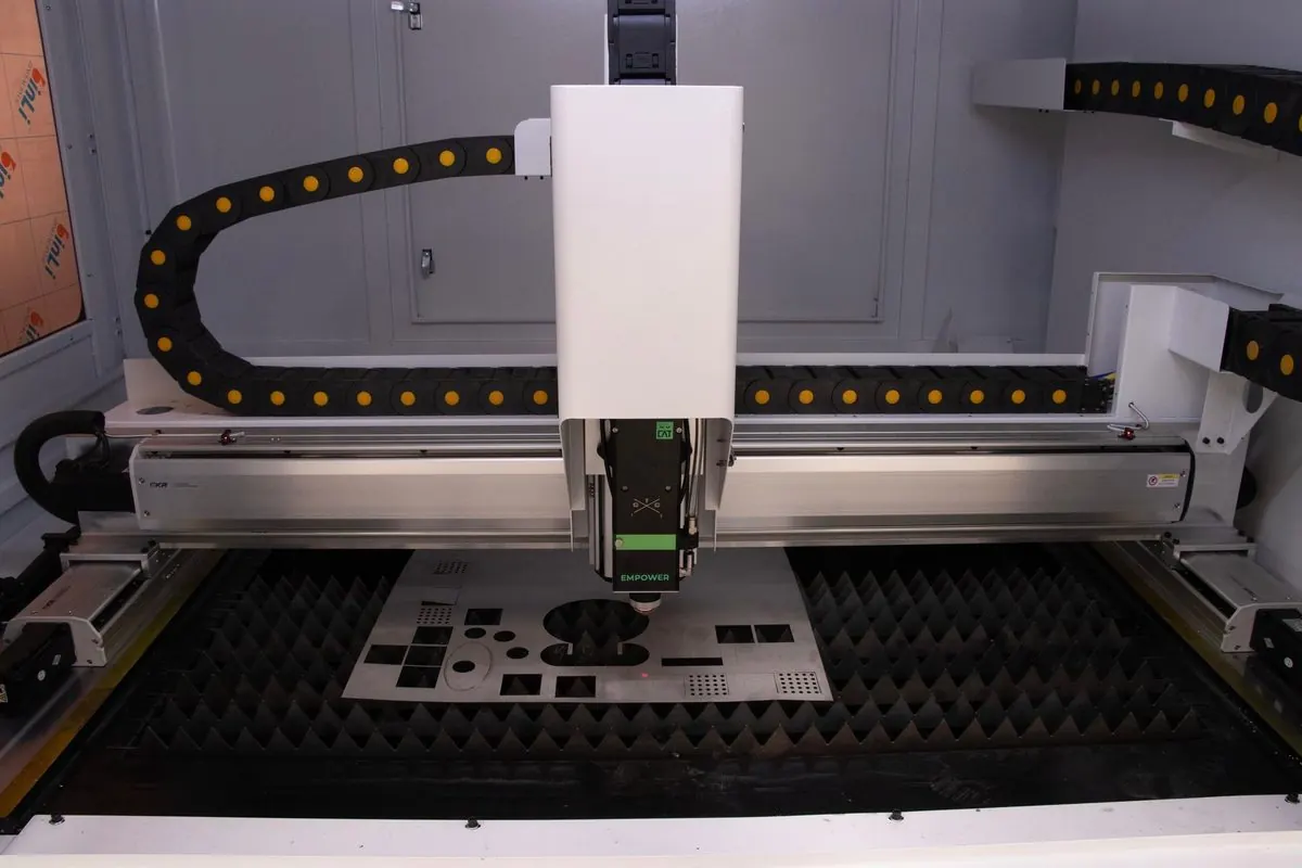Industrial laser cutting machine cutting a perforated metal sheet