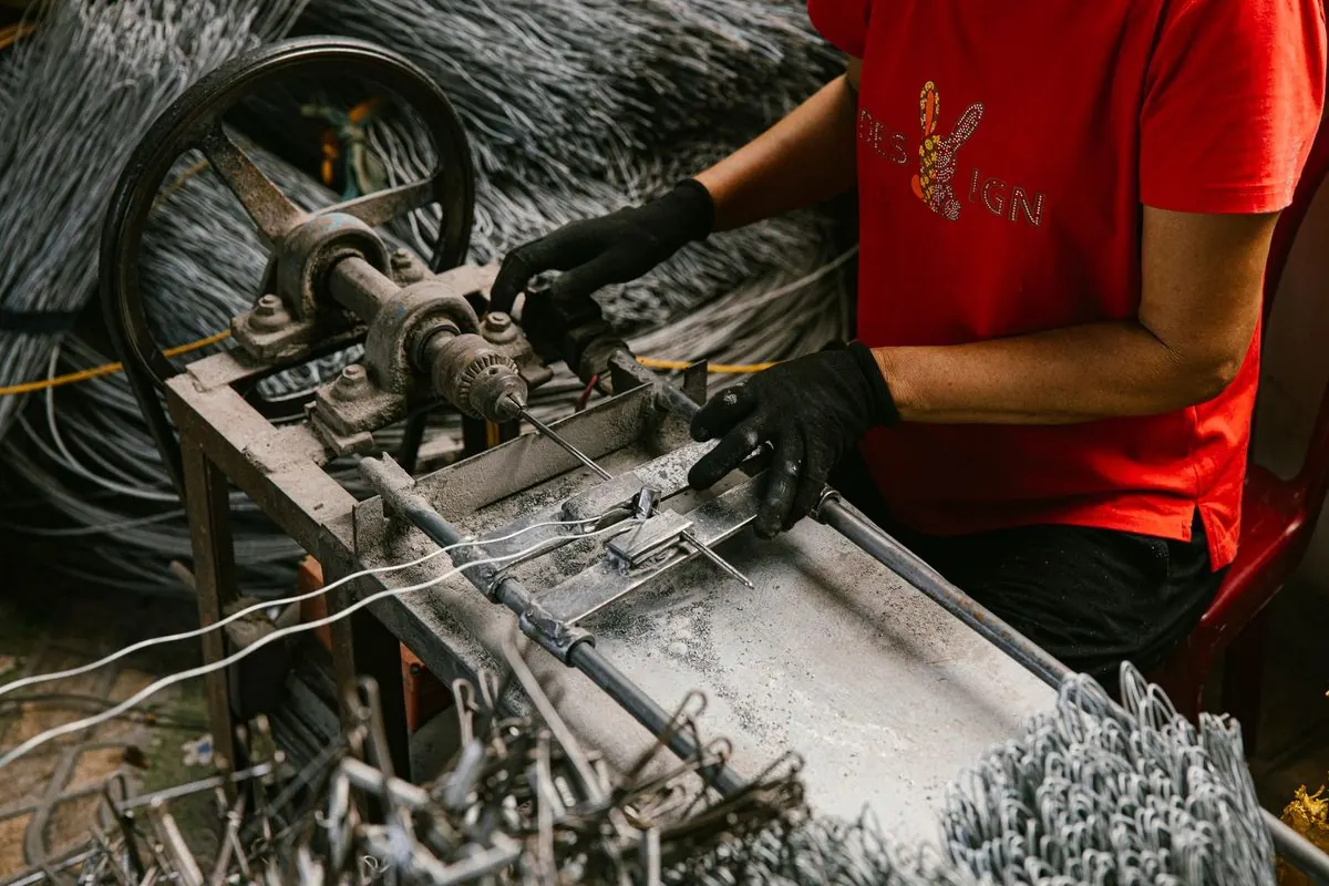 Worker in gloves operating a metal wire bending machine