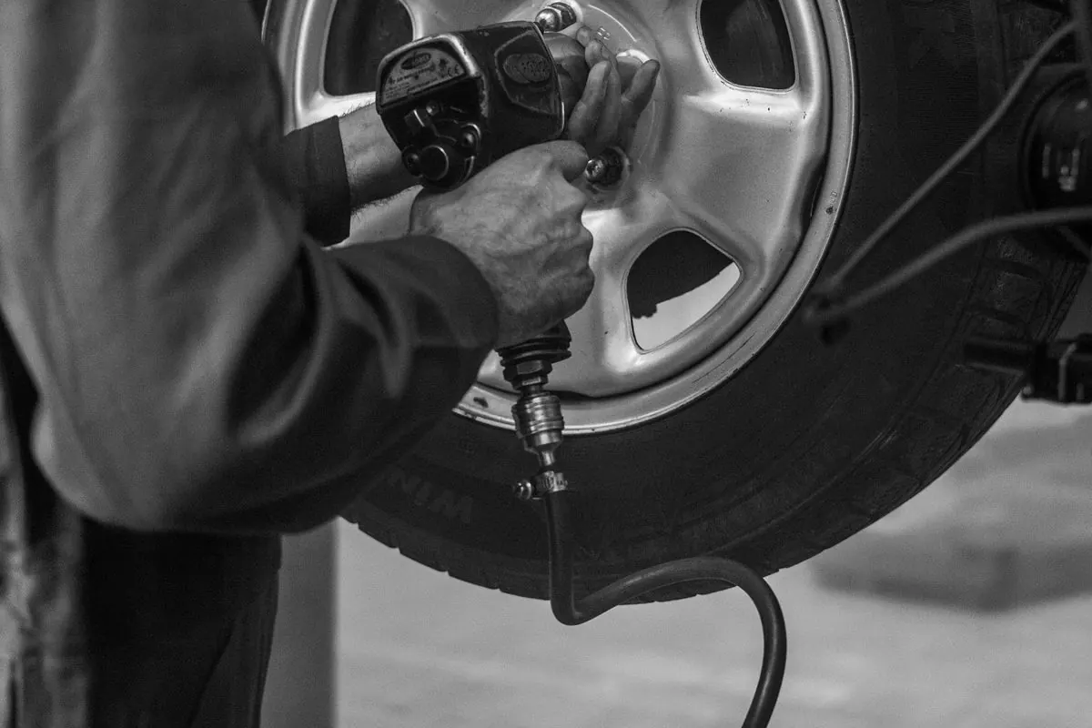 Mechanic using a pneumatic impact wrench on a car wheel