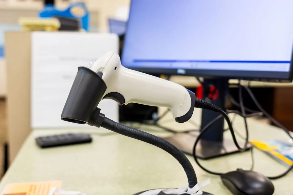 Barcode scanner on a stand beside a monitor on an office desk