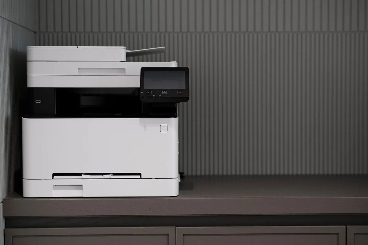 Máy photocopy đa năng màu trắng đặt trên tủ trong văn phòng