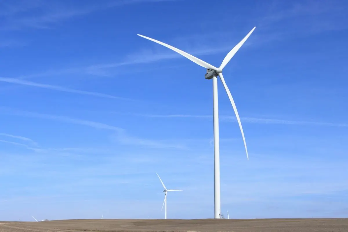 White wind turbine in a field under a blue sky