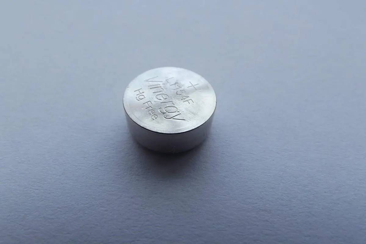 Một pin cúc áo kim loại tròn đặt trên nền xám