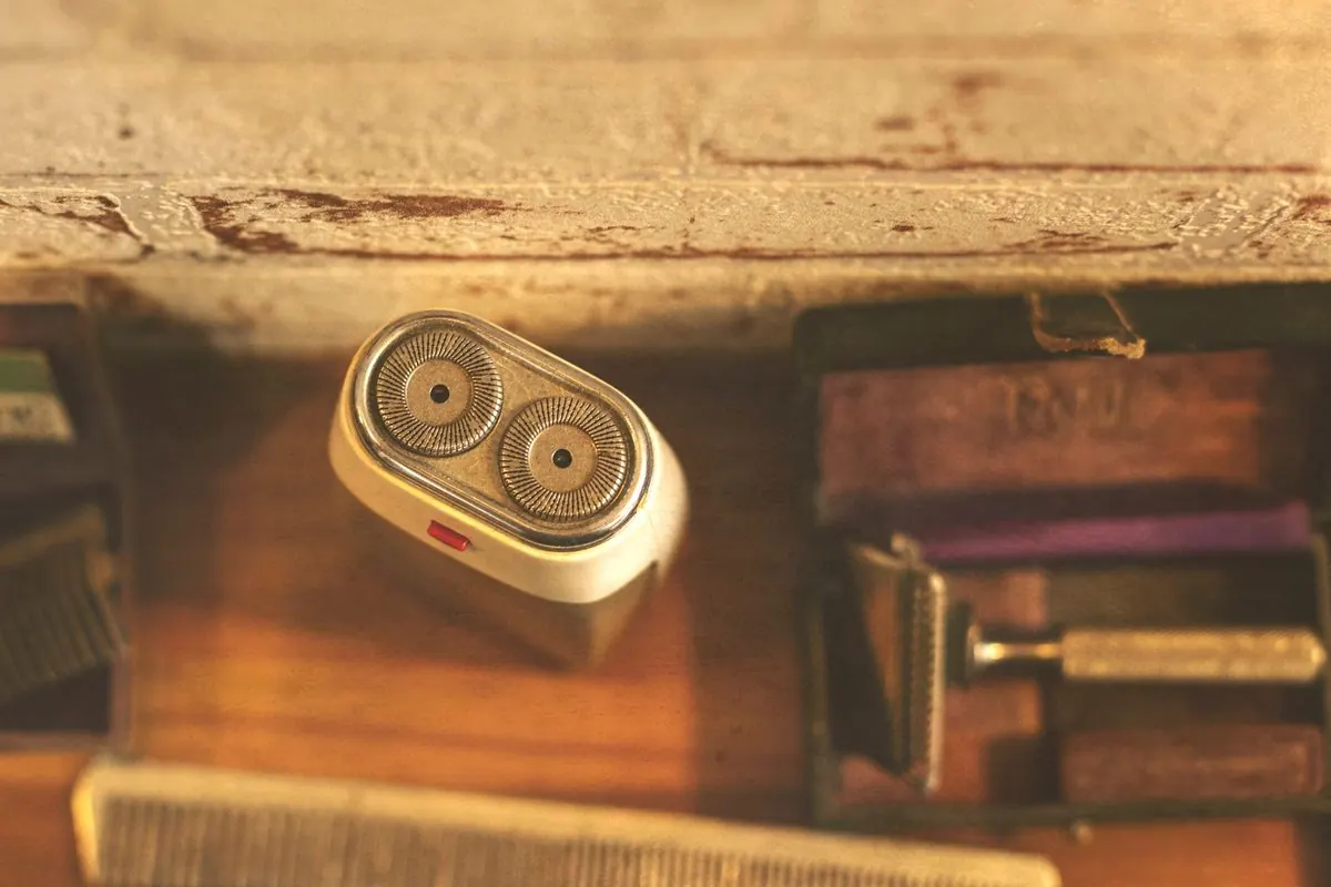 Vintage electric shaver lying next to a comb on a wooden surface