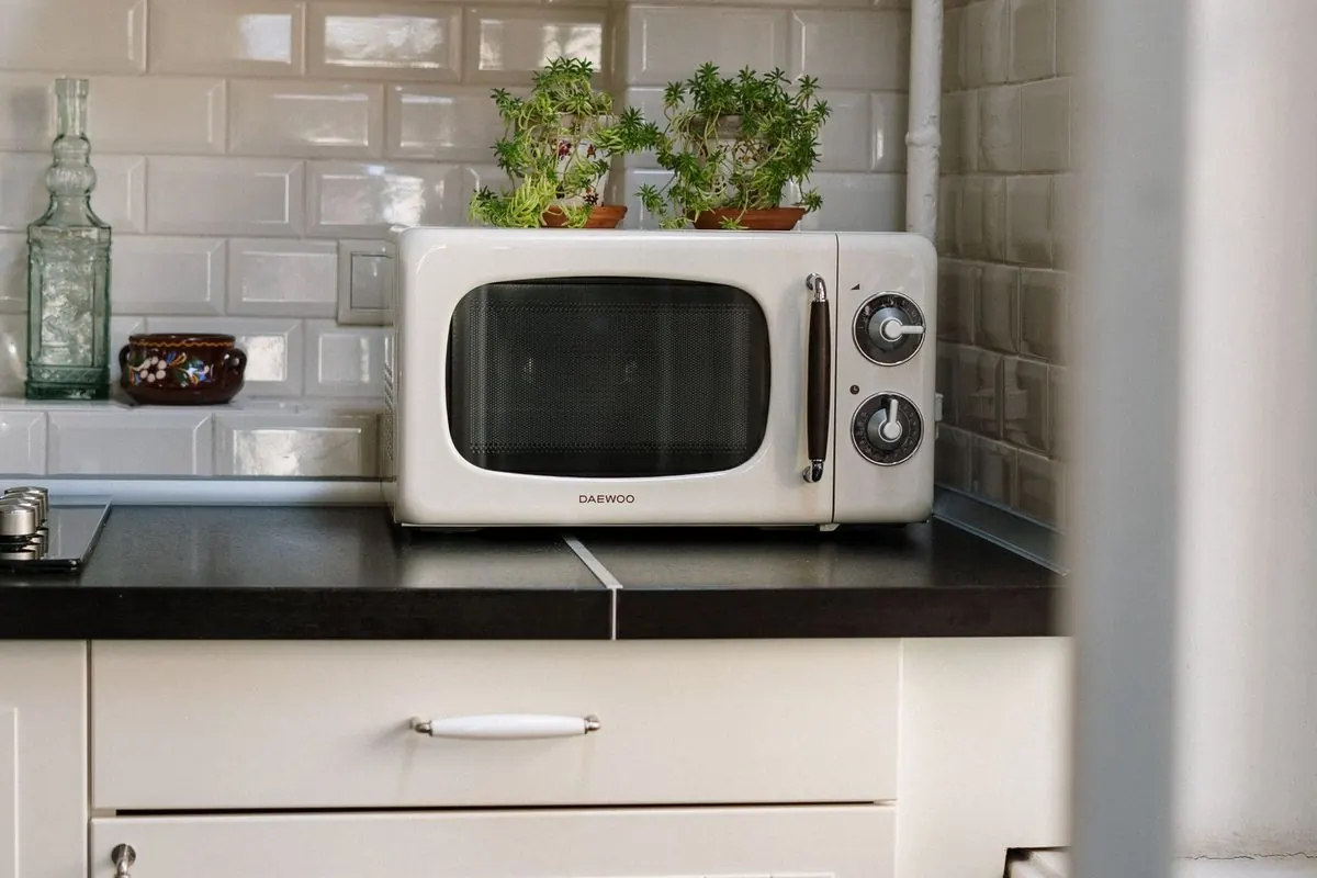 Silver microwave oven on a white kitchen cabinet
