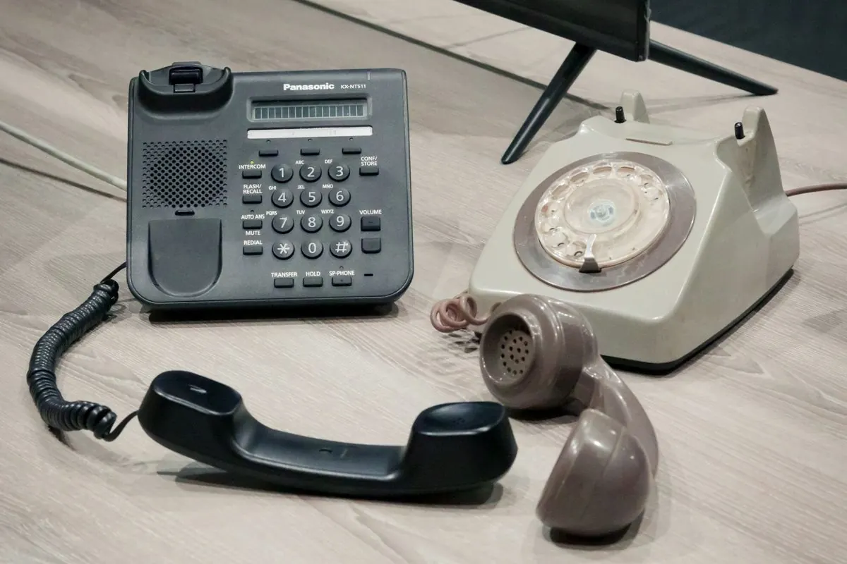 Modern and old rotary desk telephones on a table