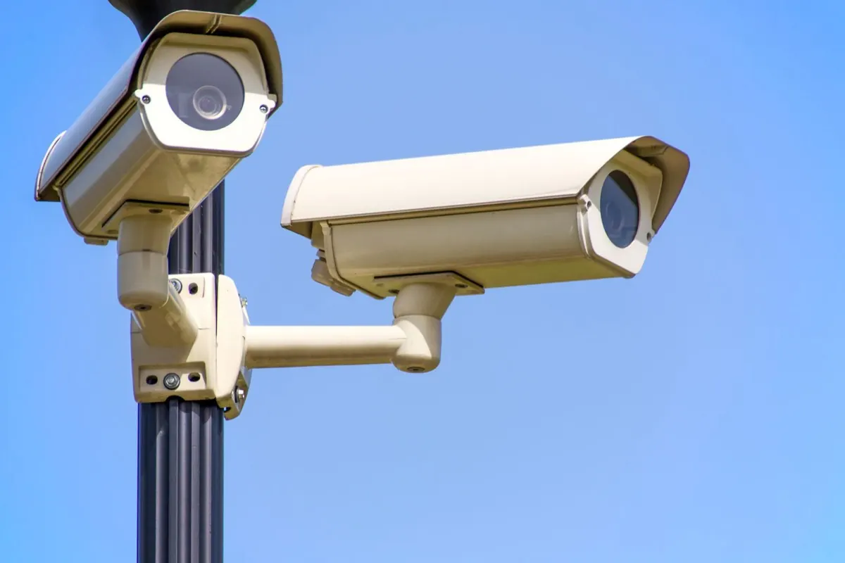 Hai camera giám sát gắn trên cột, nền trời xanh