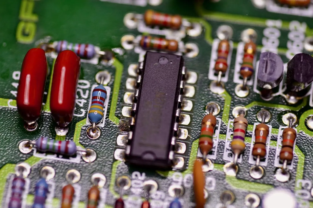 Hai tụ màng nhựa màu đỏ cạnh IC và điện trở trên bảng mạch