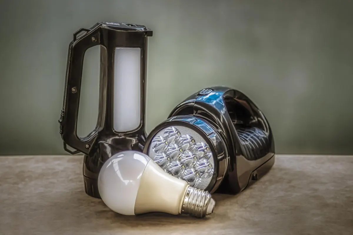 Milky-white LED bulb beside an LED torch on a stone surface