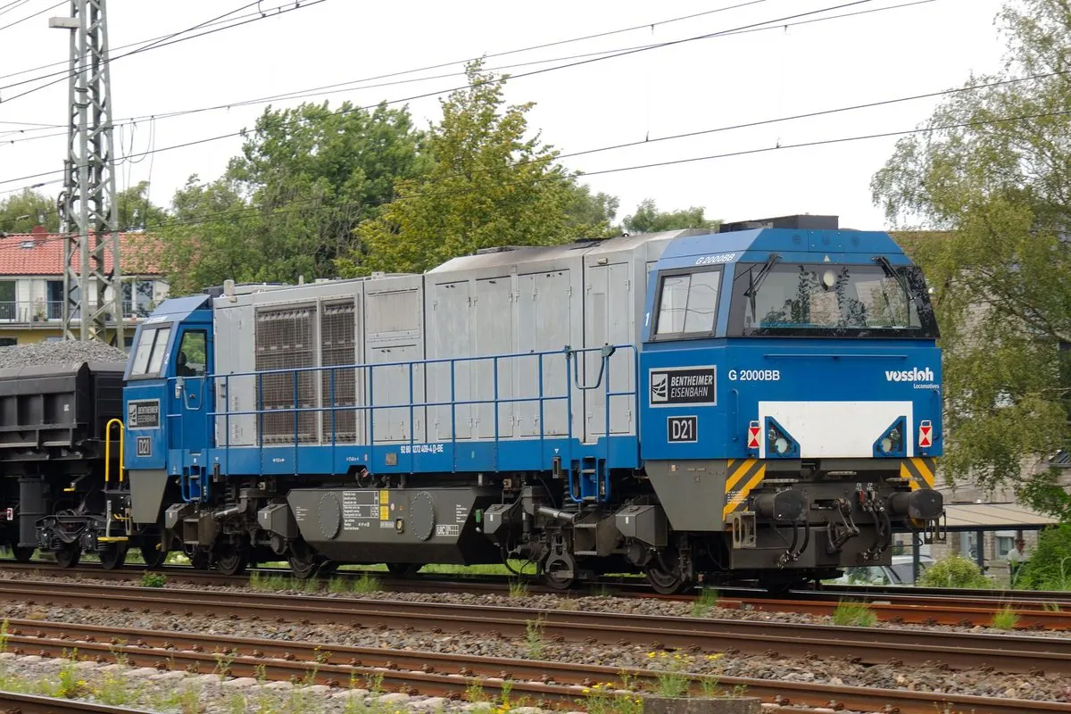 Đầu máy diesel màu xanh kéo tàu hàng trên đường ray