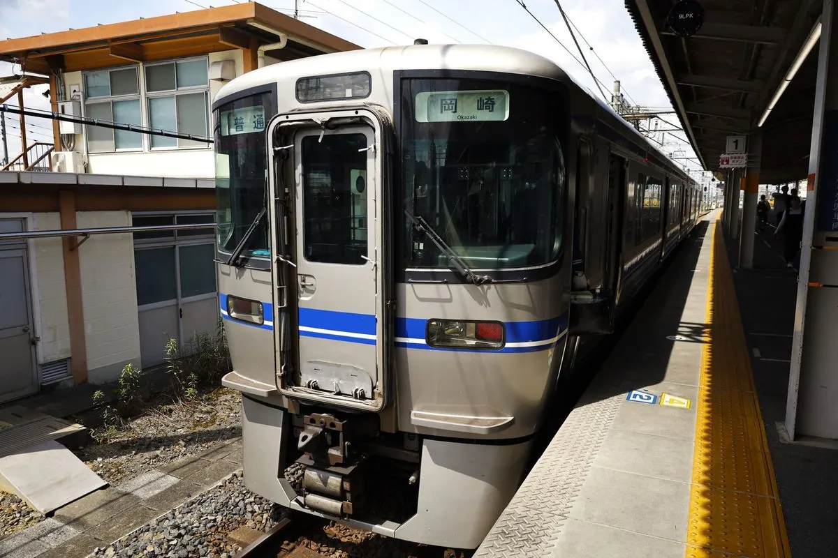 Silver electric railcar with blue stripe at a platform
