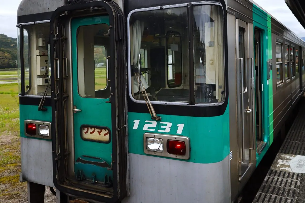 Green self-propelled railcar at a platform