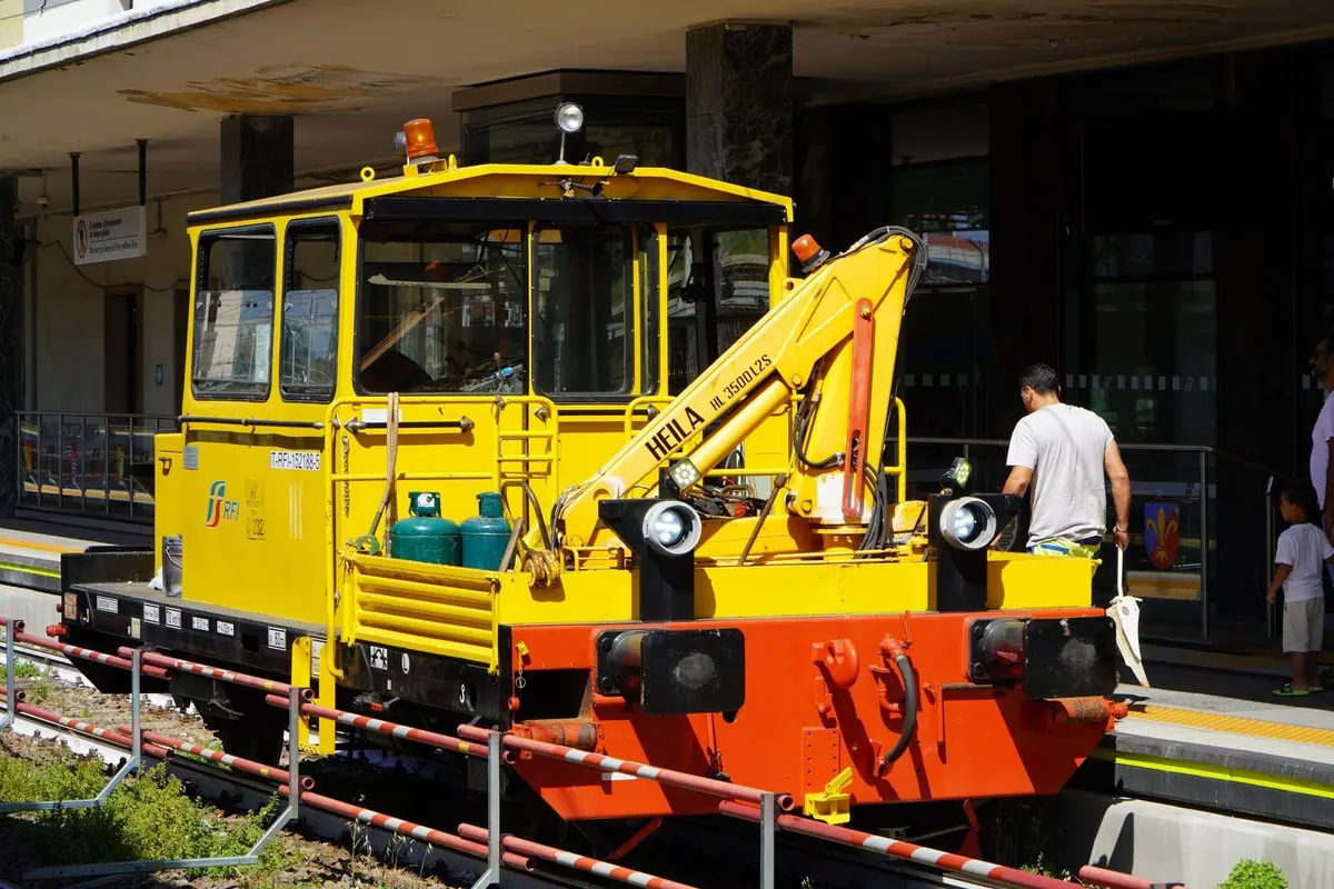 Yellow railway maintenance vehicle with crane at a station