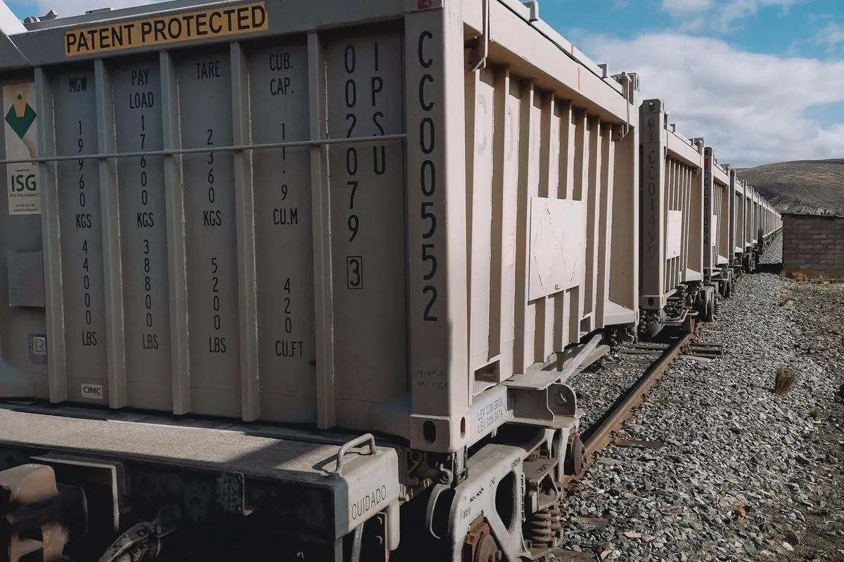 Row of grey freight wagons on gravel railway