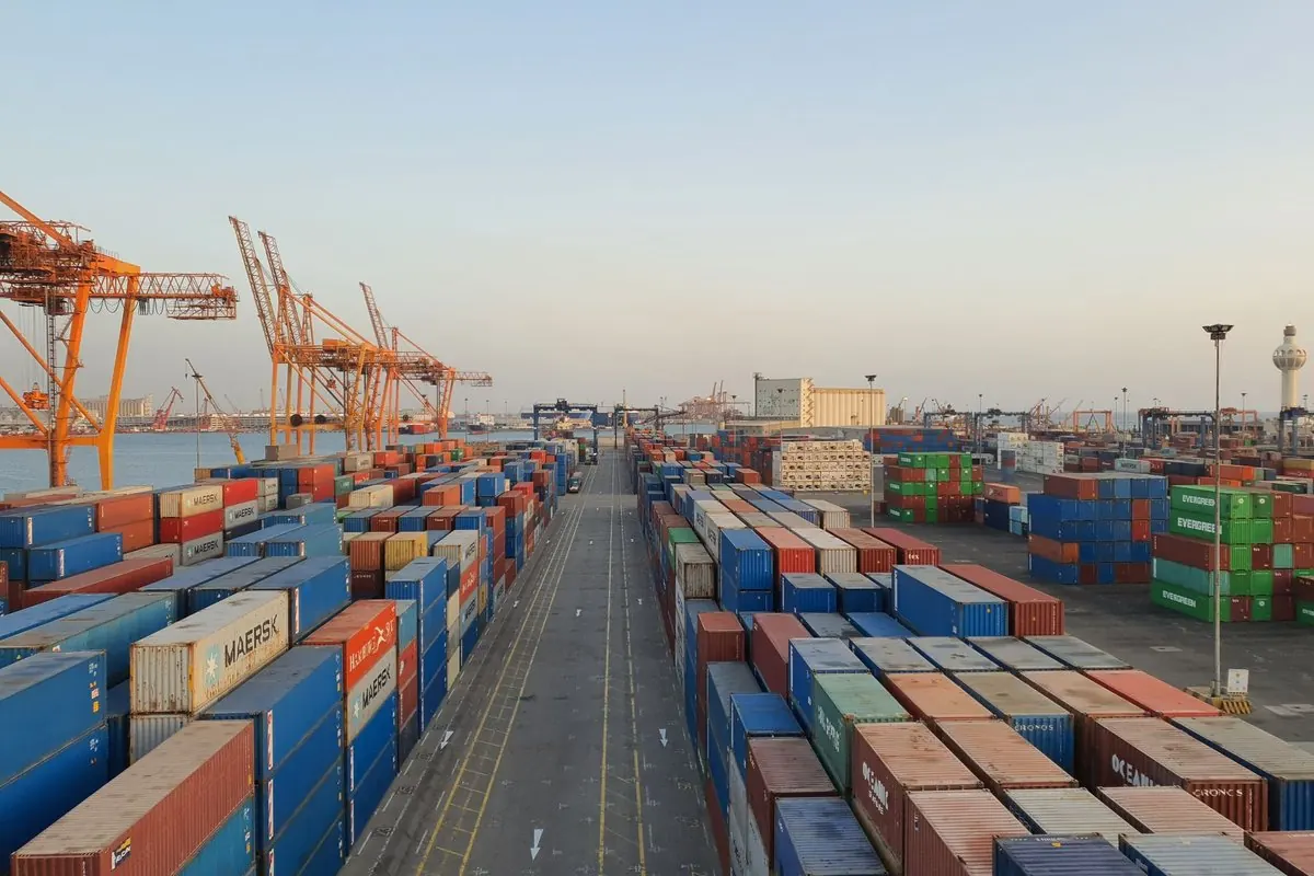 Bãi container xếp chồng nhiều màu tại cảng, cần cẩu phía xa