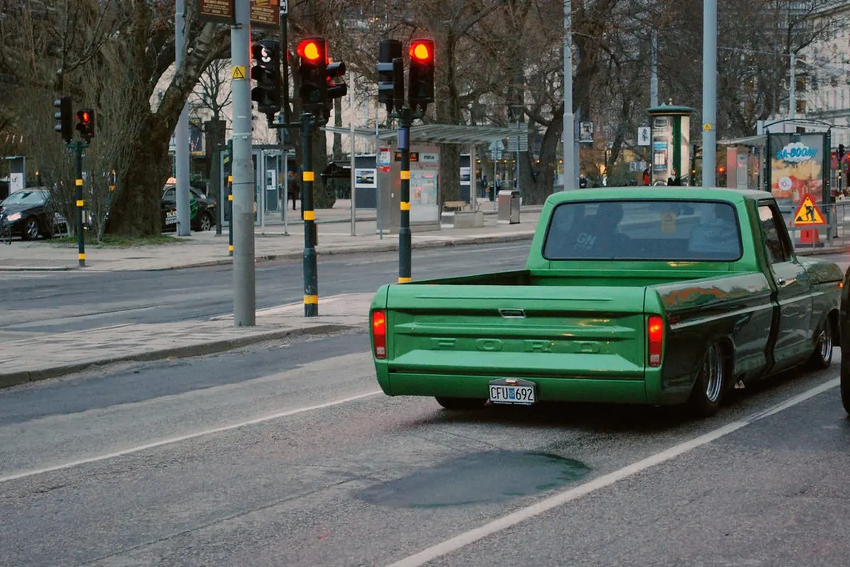 Xe bán tải xanh lá đi qua đèn giao thông