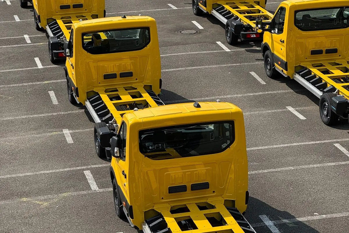 Row of yellow truck chassis without bodies in a parking lot