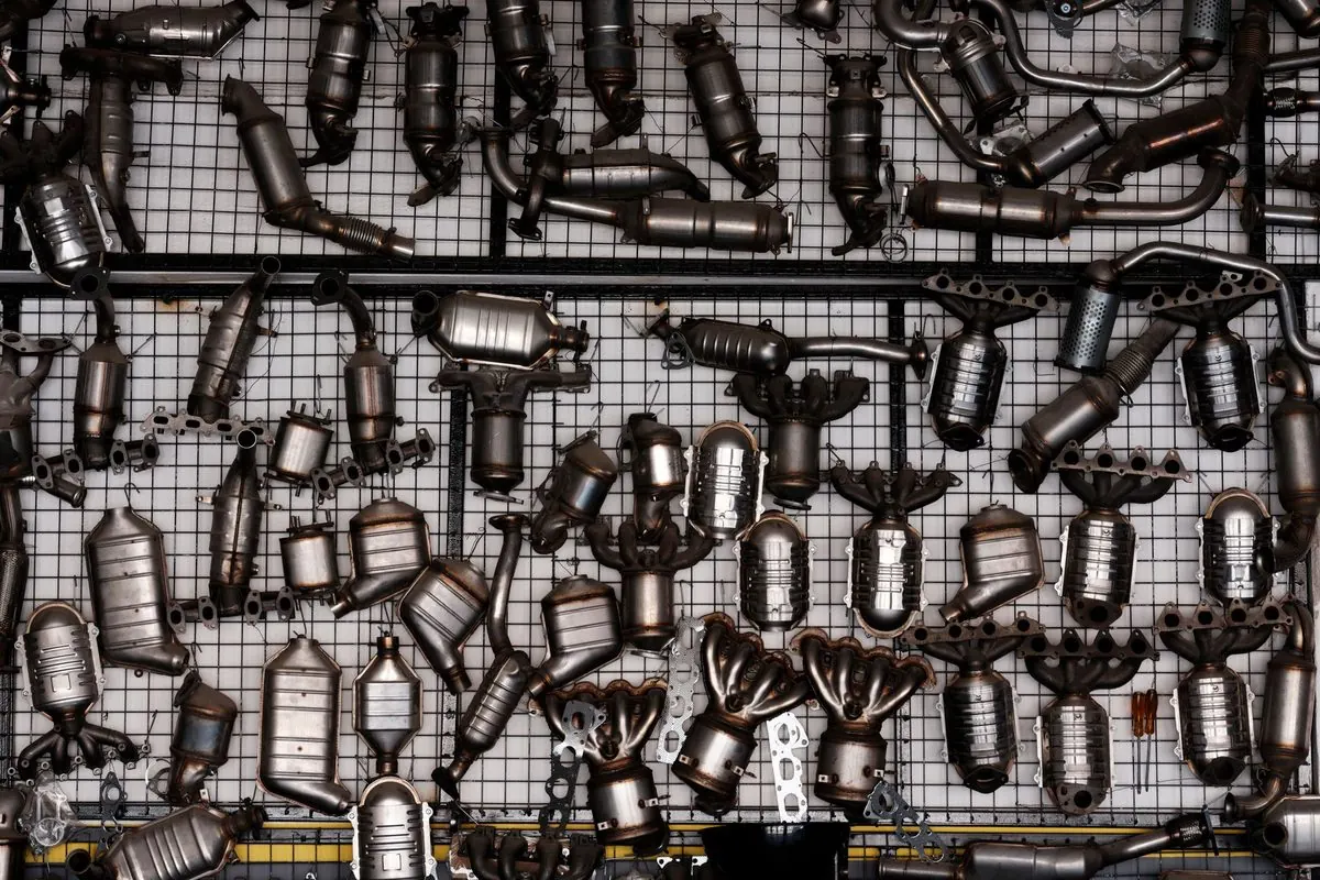 Many car exhaust pipes and mufflers hung on a rack