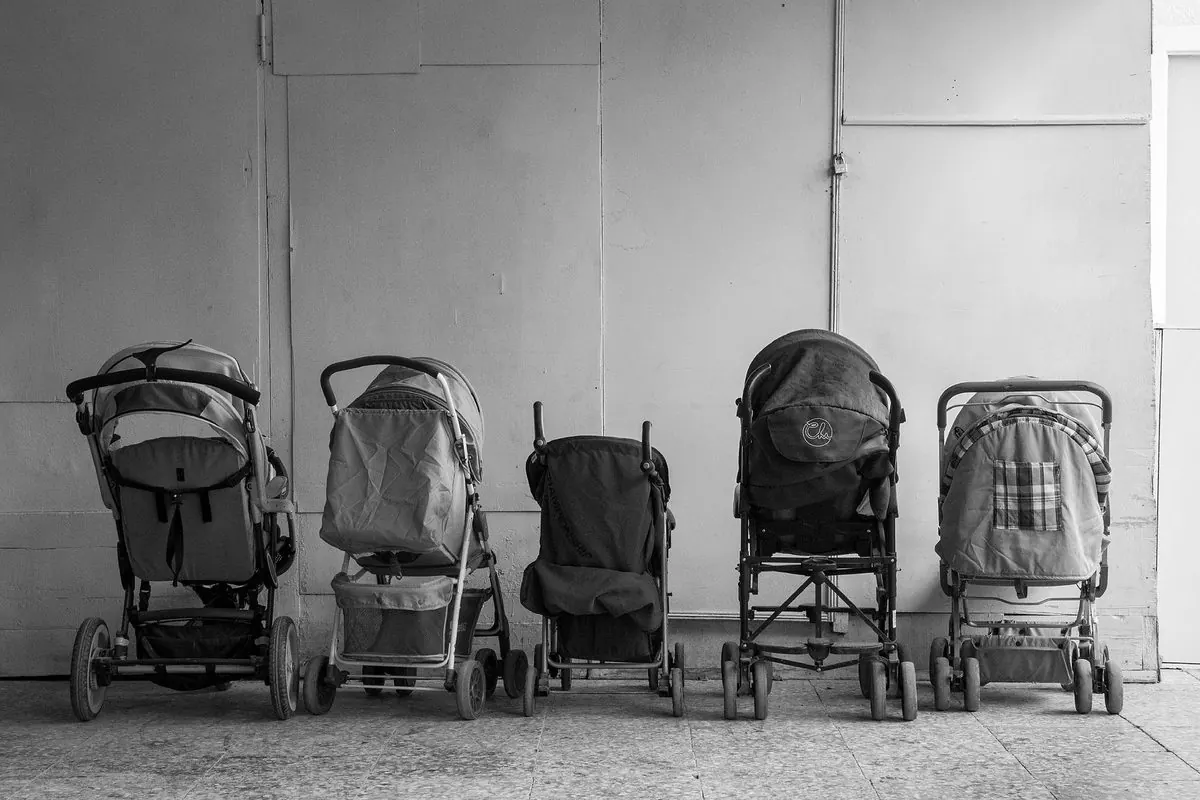 Row of baby strollers lined up against a wall