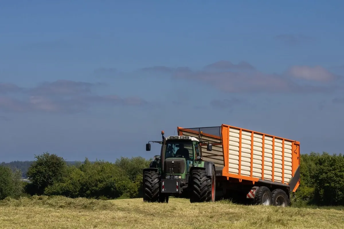 Tractor pulling a farm loader wagon in a field