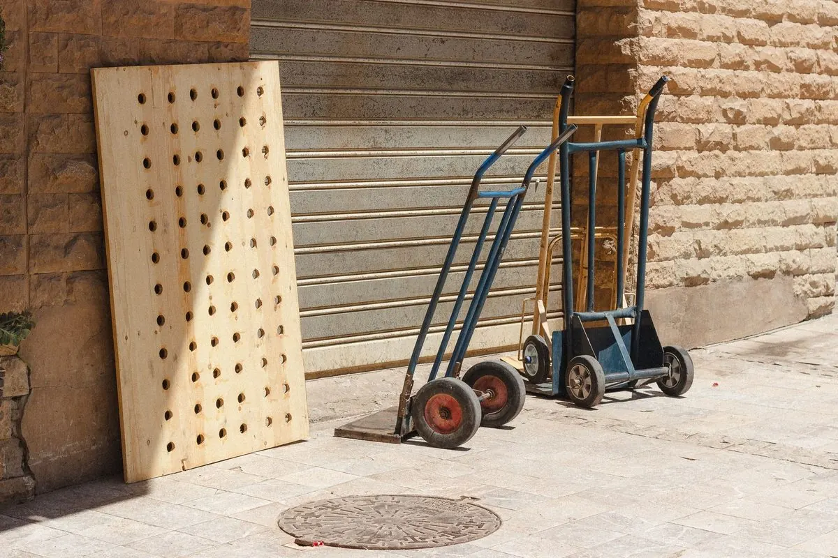 Two two-wheeled hand trucks leaning against a wall