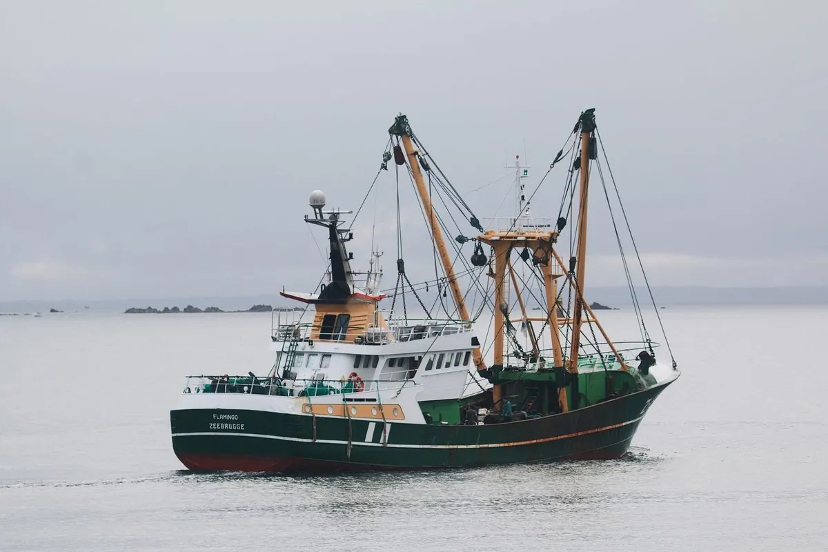 Beam trawler fishing vessel with two outrigger booms at sea