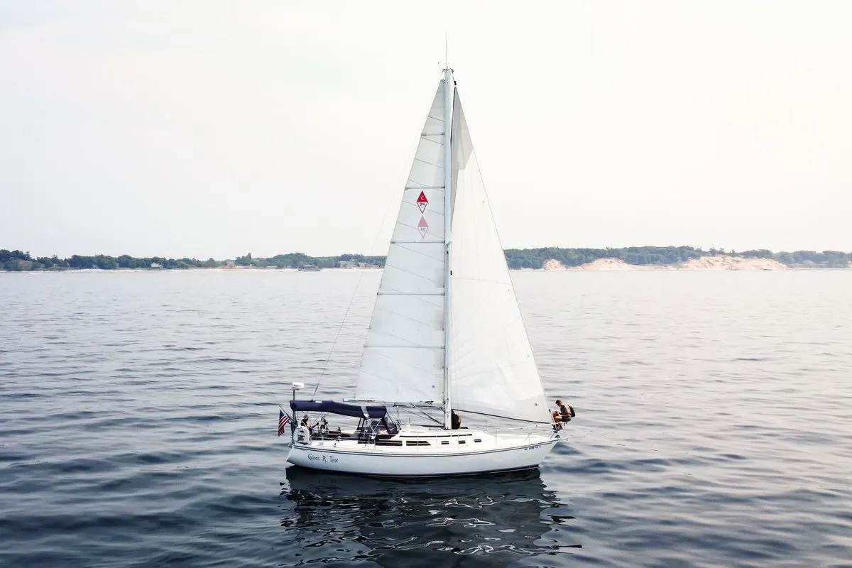 White sailboat under sail on calm water