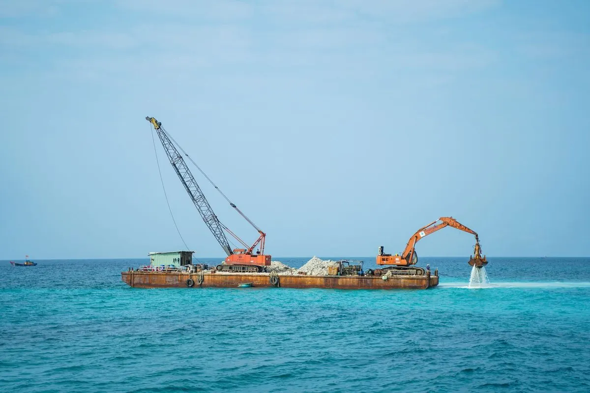 Floating barge with a crane and an excavator at sea