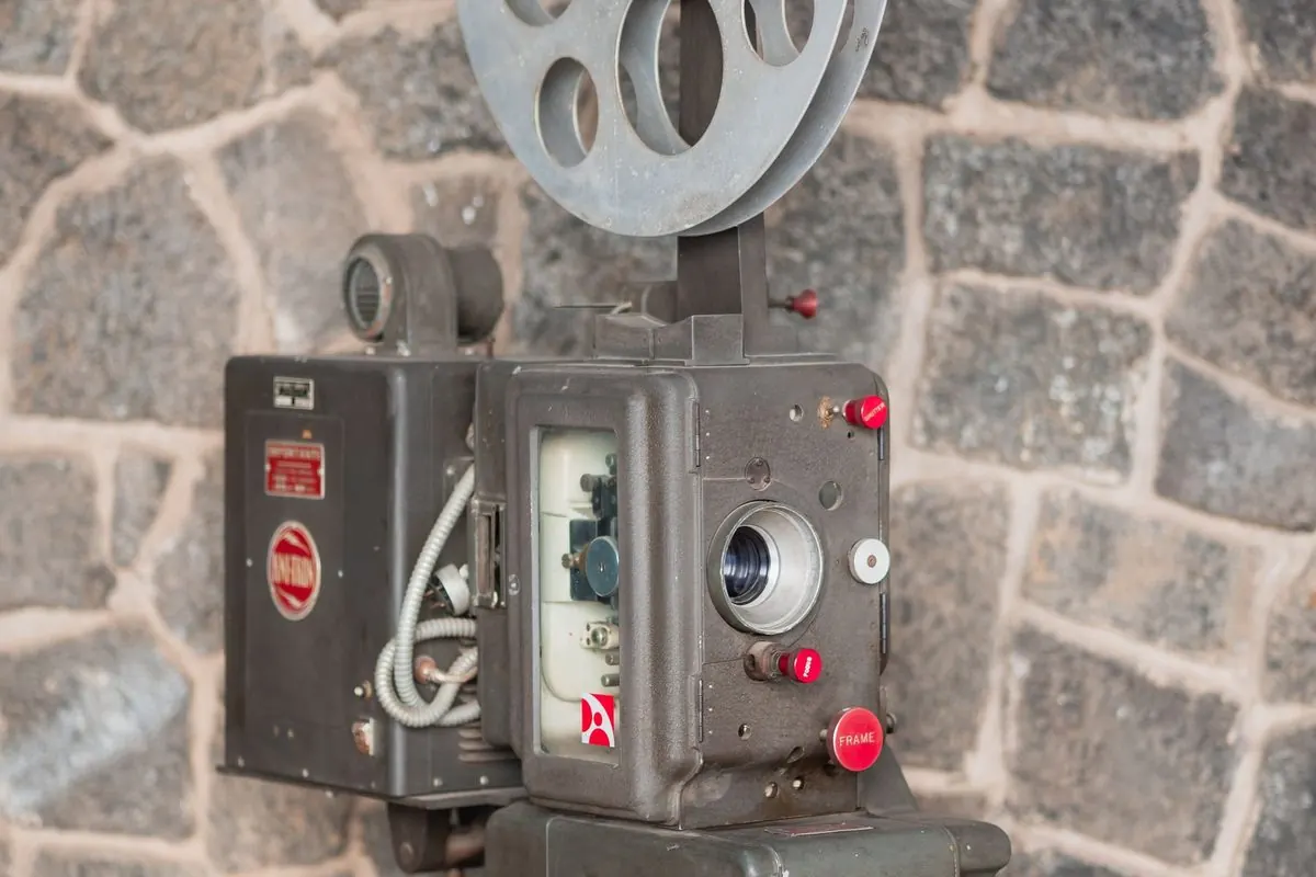 Vintage film projector with a reel against a stone wall