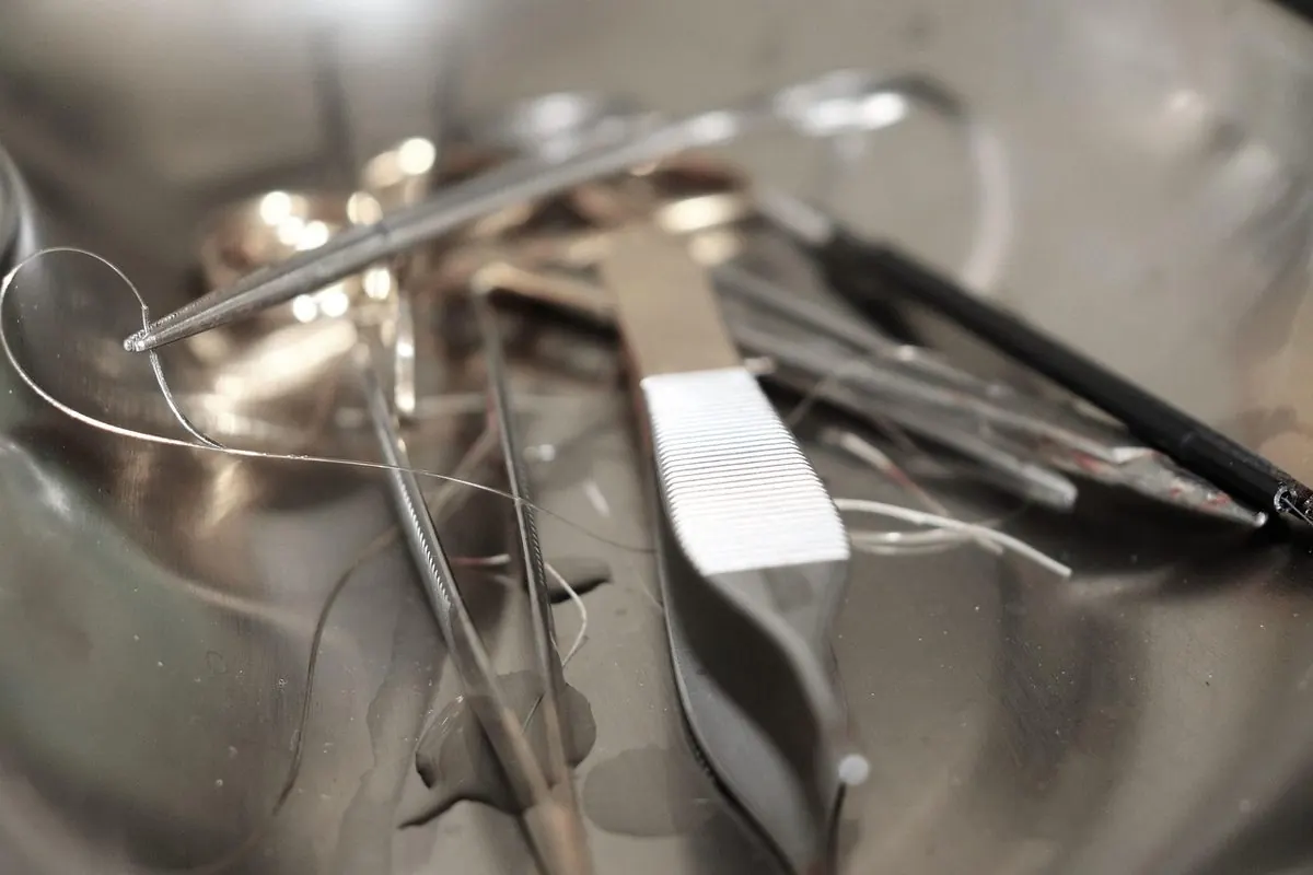 Dụng cụ phẫu thuật bằng thép và chỉ khâu trong khay inox