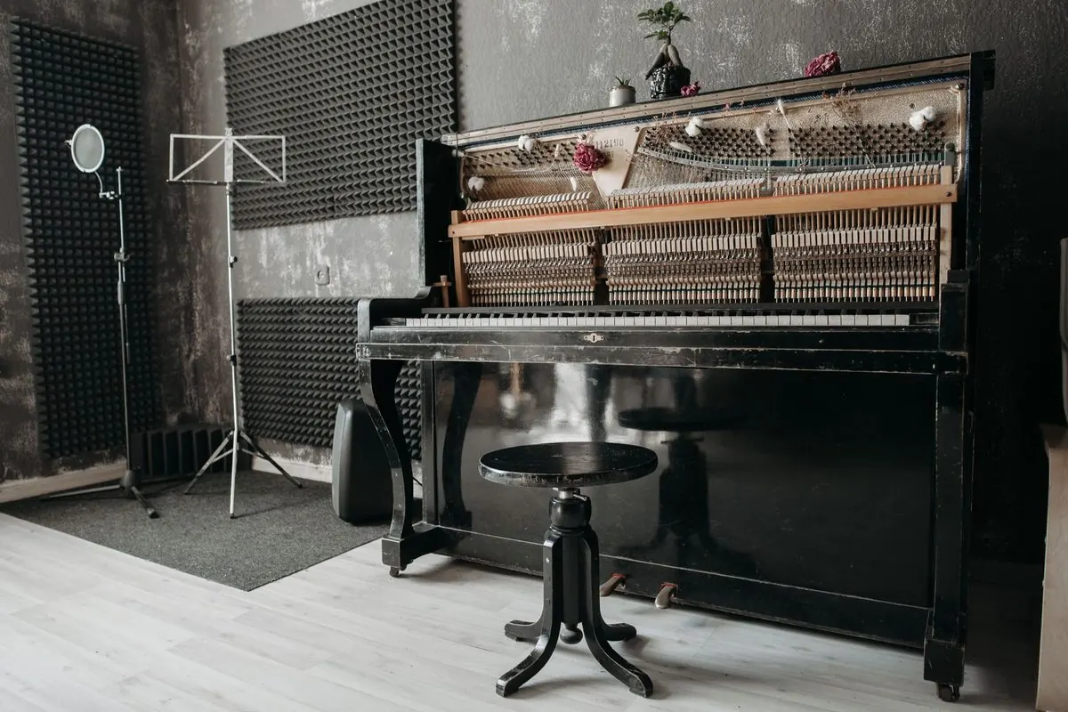 Đàn piano đứng màu đen cùng ghế xoay trong phòng thu
