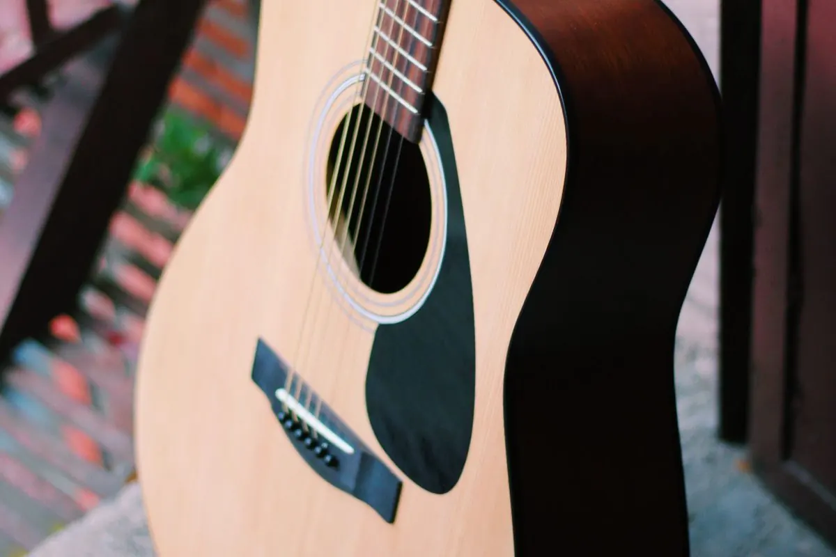 Đàn guitar acoustic gỗ nâu dựng cạnh bậc thang