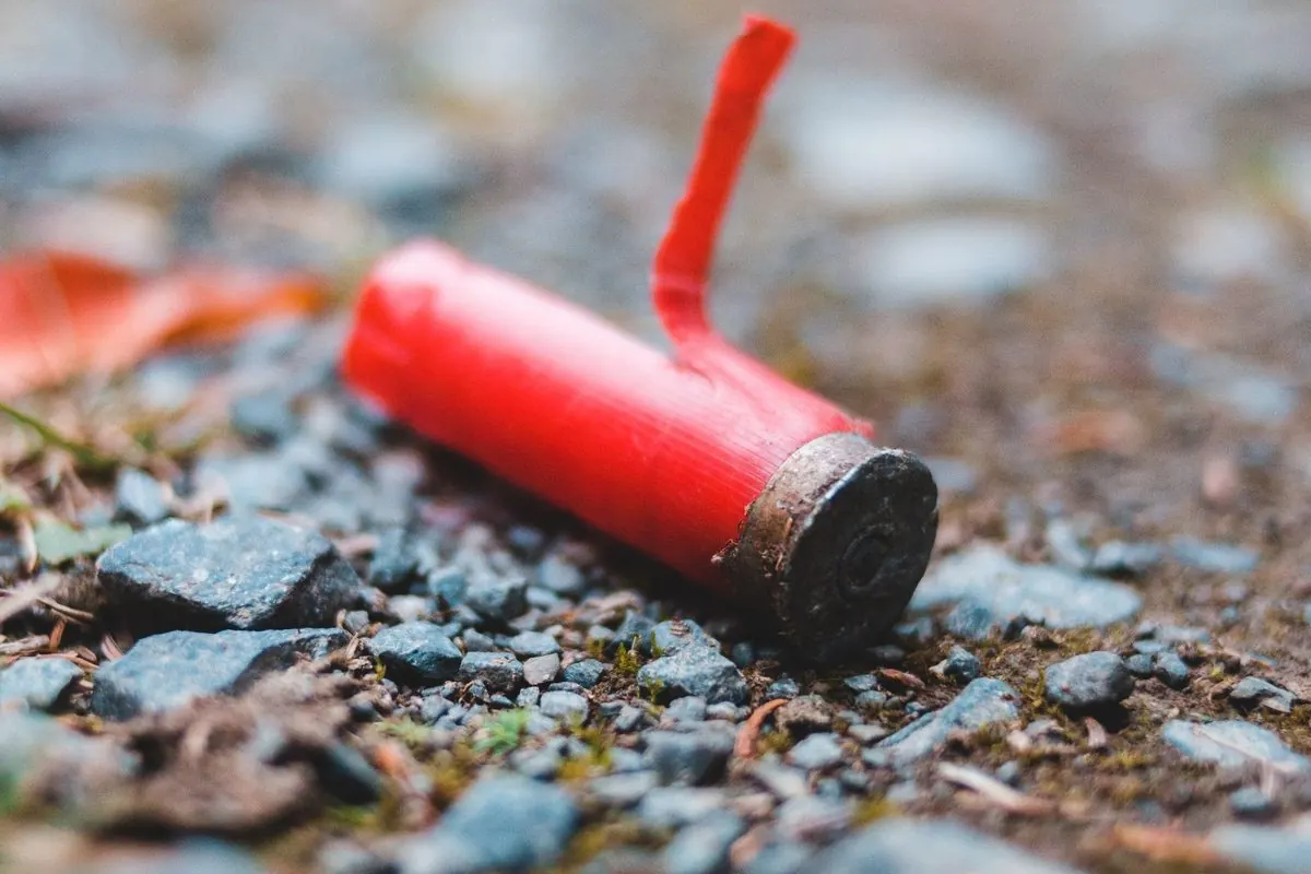 Vỏ đạn shotgun màu đỏ nằm trên nền sỏi đá