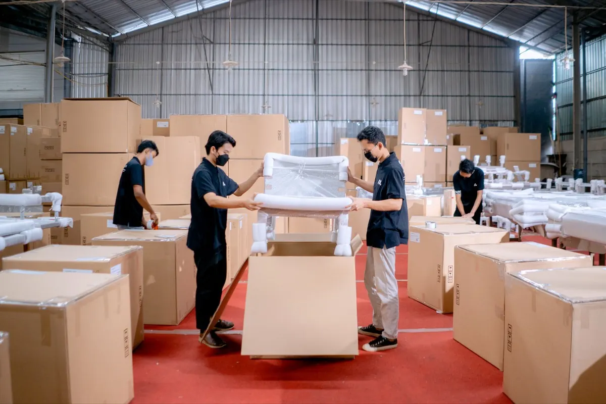 Công nhân đóng thùng carton ghế đã bọc màng trong kho xưởng nội thất