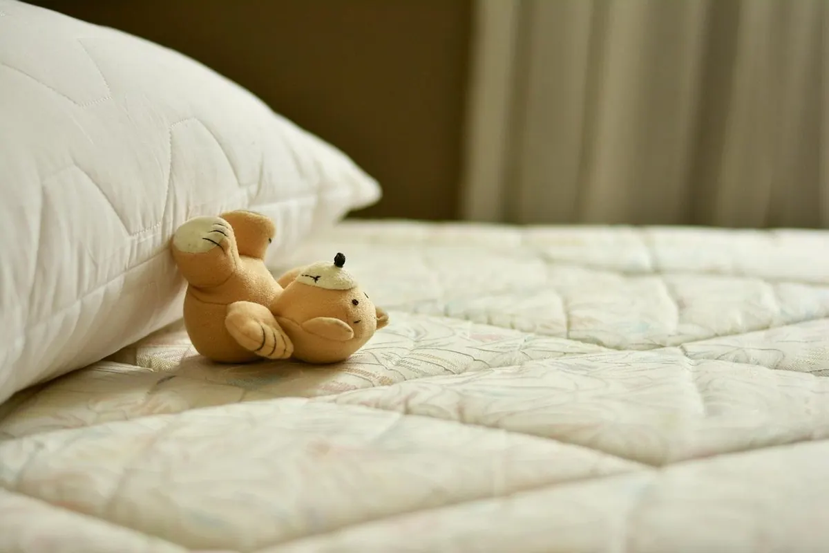 Mặt nệm chần bông màu kem với gối và gấu bông