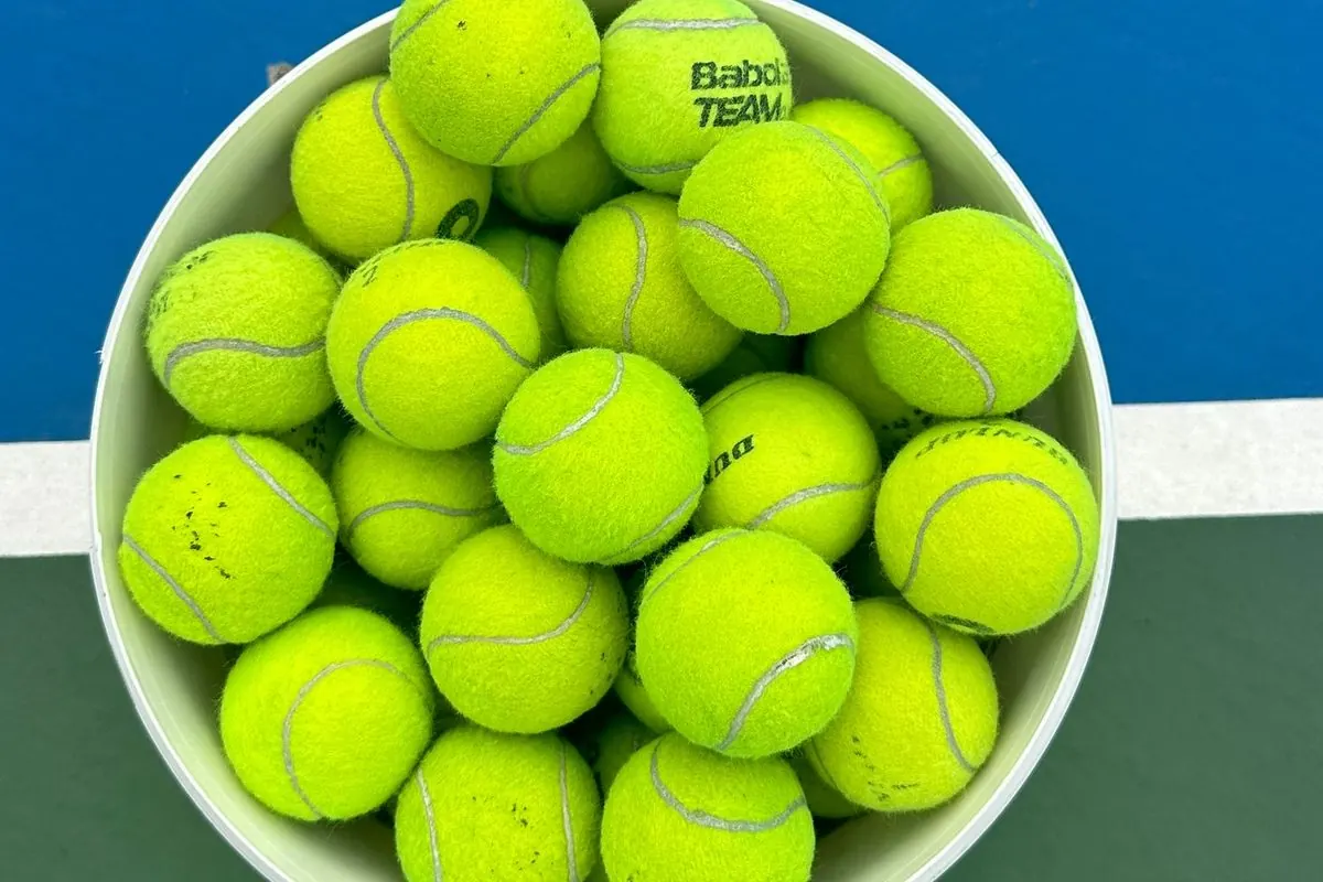 Bucket full of tennis balls on a court