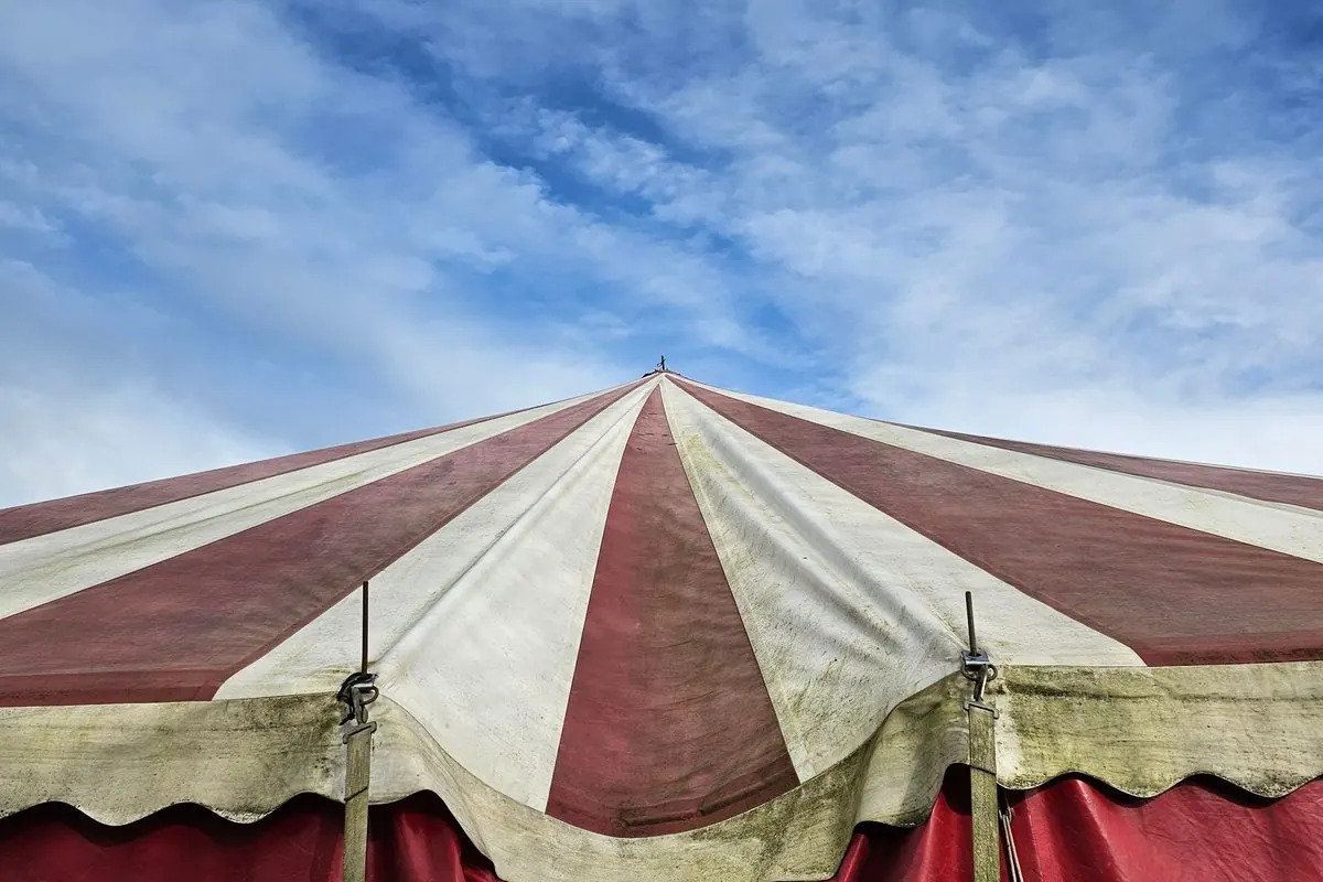 Red and white striped circus tent roof under a blue sky
