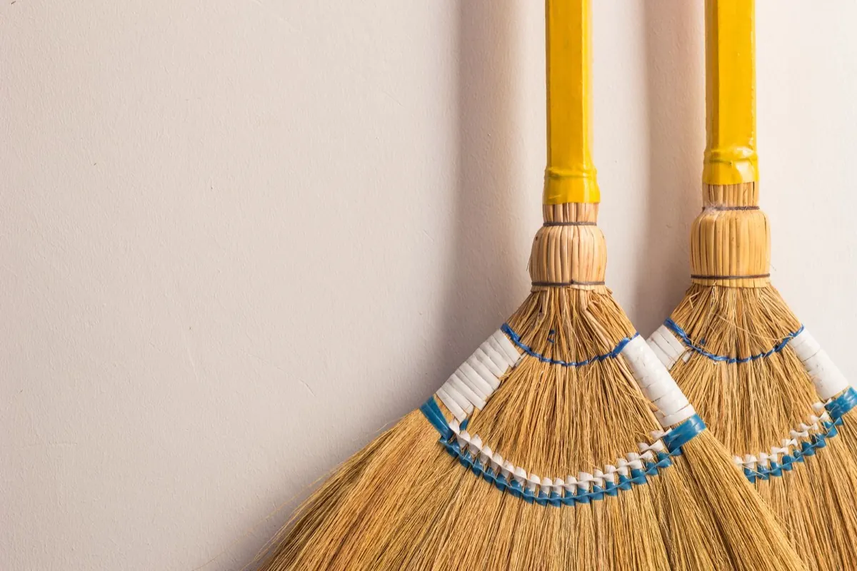 Hai cây chổi bó từ cọng thực vật dựng bên tường