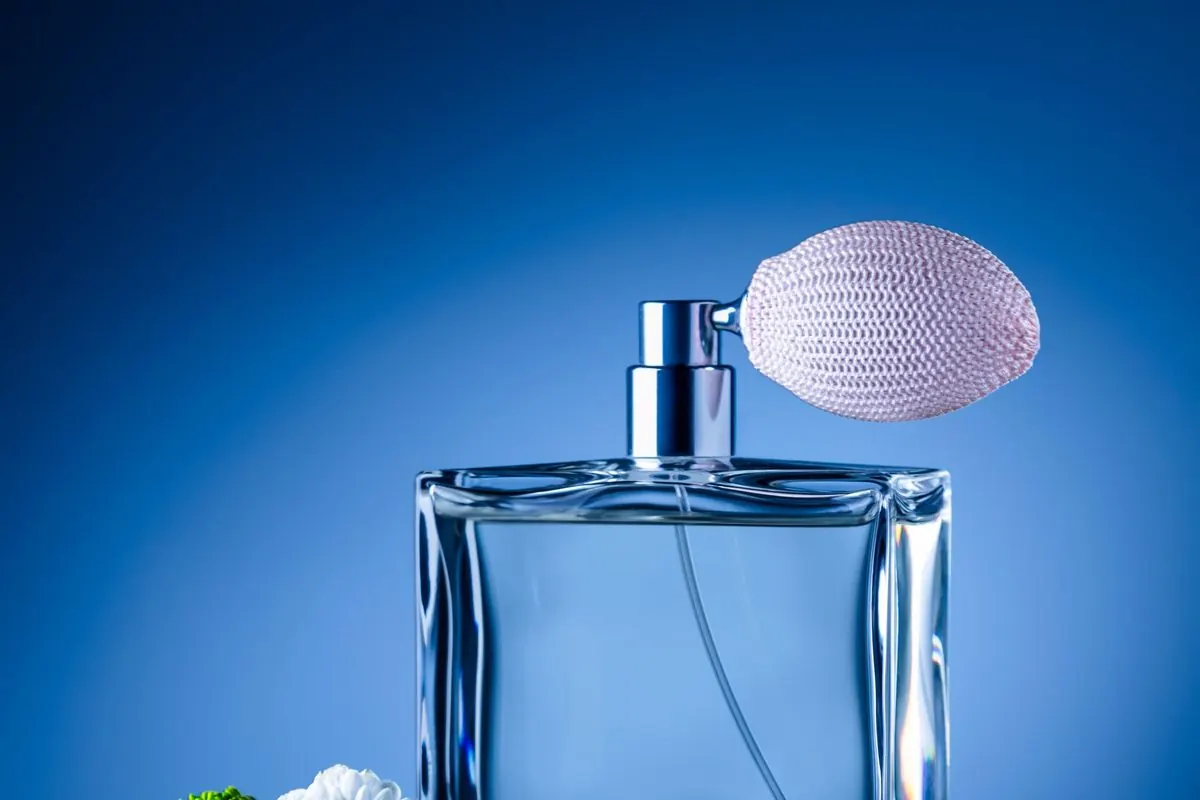 Lọ nước hoa thủy tinh xanh có bóp xịt cạnh hoa trắng