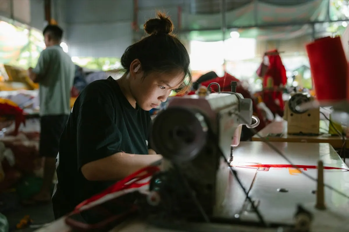 Nữ công nhân may vải trên máy may công nghiệp trong xưởng may