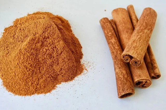 Quế thanh cuộn và đống bột quế trên mặt bàn trắng